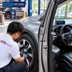 Kỹ thuật viên HTD kiểm tra áp suất lốp bằng đồng hồ đo cầm tay để đối chiếu với màn hình TPMS HTD TP-D24 trên ô tô